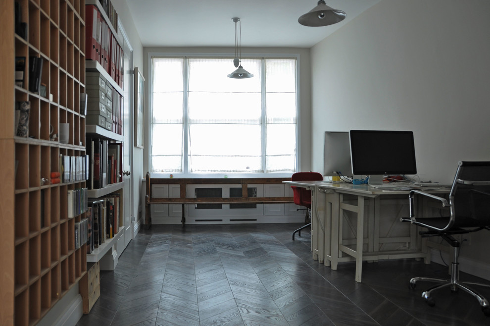 This is an example of a mid-sized contemporary study room in London with white walls, dark hardwood floors, no fireplace and a freestanding desk.
