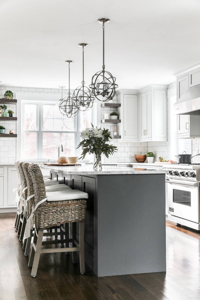 Inspiration for a transitional l-shaped kitchen in Boston with white cabinets, quartz benchtops, white splashback, subway tile splashback, stainless steel appliances, with island, brown floor, shaker cabinets and dark hardwood floors.