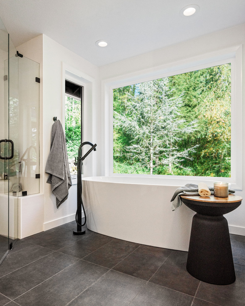 Design ideas for a mid-sized modern master bathroom in Portland with flat-panel cabinets, brown cabinets, a freestanding tub, a curbless shower, a wall-mount toilet, white tile, white walls, an undermount sink, quartzite benchtops, black floor, a hinged shower door, grey benchtops, a shower seat, a double vanity and a floating vanity.