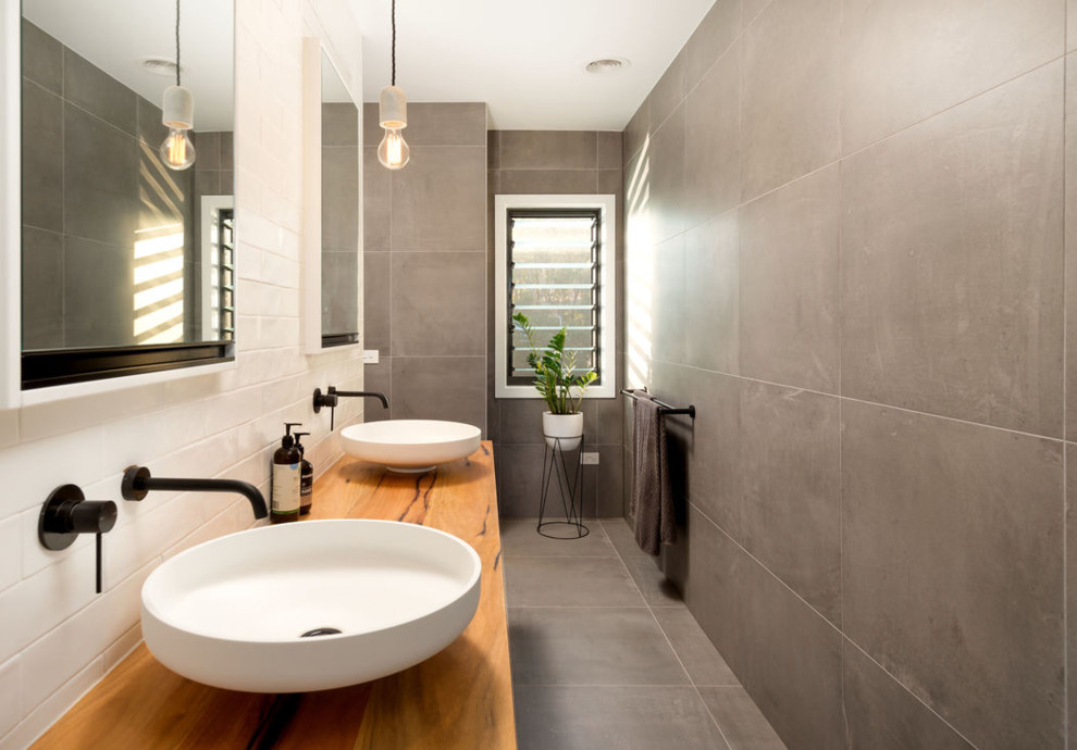 This is an example of a mid-sized contemporary master bathroom in Other with light wood cabinets, an alcove shower, gray tile, porcelain tile, grey walls, porcelain floors, a vessel sink, wood benchtops, grey floor and an open shower.
