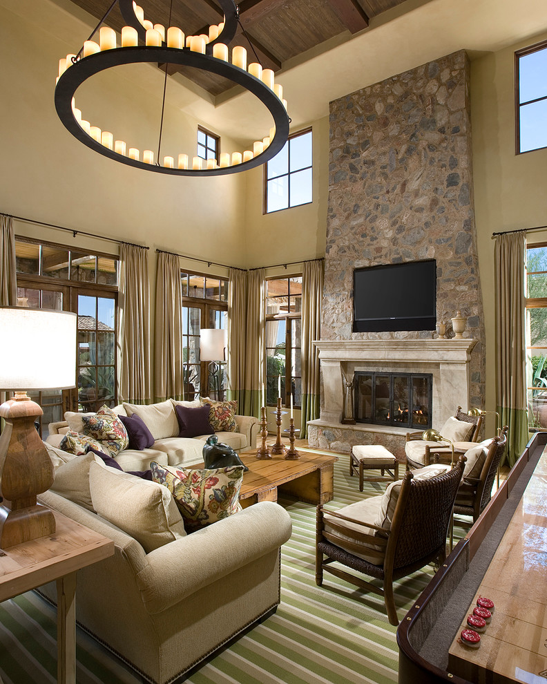 Large mediterranean open concept family room in Phoenix with beige walls, a stone fireplace surround, a game room, carpet, a standard fireplace, a built-in media wall and green floor.