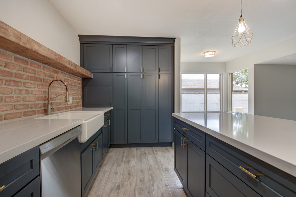 Inspiration for a mid-sized transitional u-shaped porcelain tile and gray floor eat-in kitchen remodel in Phoenix with a farmhouse sink, shaker cabinets, blue cabinets, quartz countertops, red backsplash, brick backsplash, stainless steel appliances, an island and white countertops