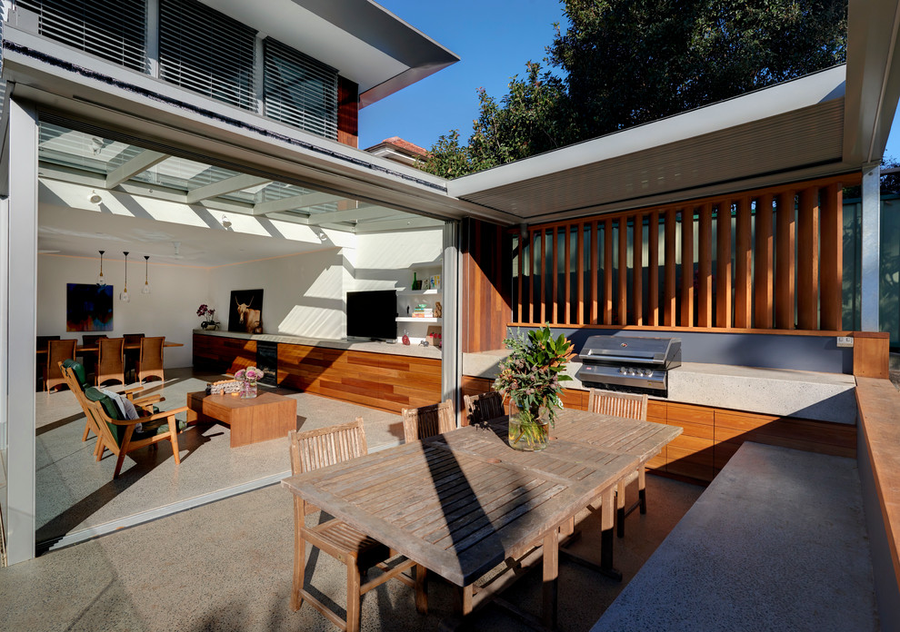 Large contemporary backyard patio in Sydney with an outdoor kitchen, concrete slab and an awning.
