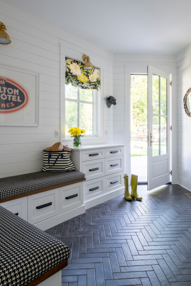 Photo of a mid-sized beach style mudroom in Minneapolis with white walls, ceramic floors, a single front door, a white front door, black floor and planked wall panelling.
