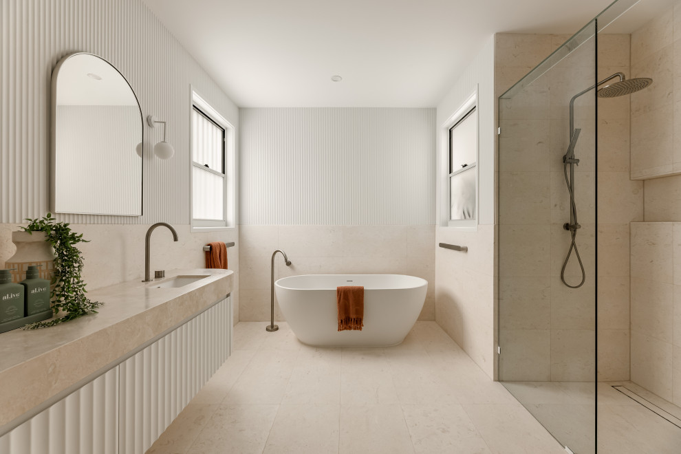 Design ideas for a modern ensuite bathroom in Brisbane with white cabinets, a freestanding bath, a walk-in shower, beige tiles, white walls, a submerged sink, beige floors, beige worktops, double sinks and a floating vanity unit.