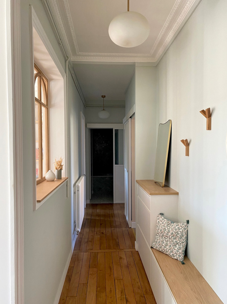 Idée de décoration pour une entrée minimaliste de taille moyenne avec un couloir, un mur vert, parquet clair, une porte double, une porte blanche, un sol marron et boiseries.