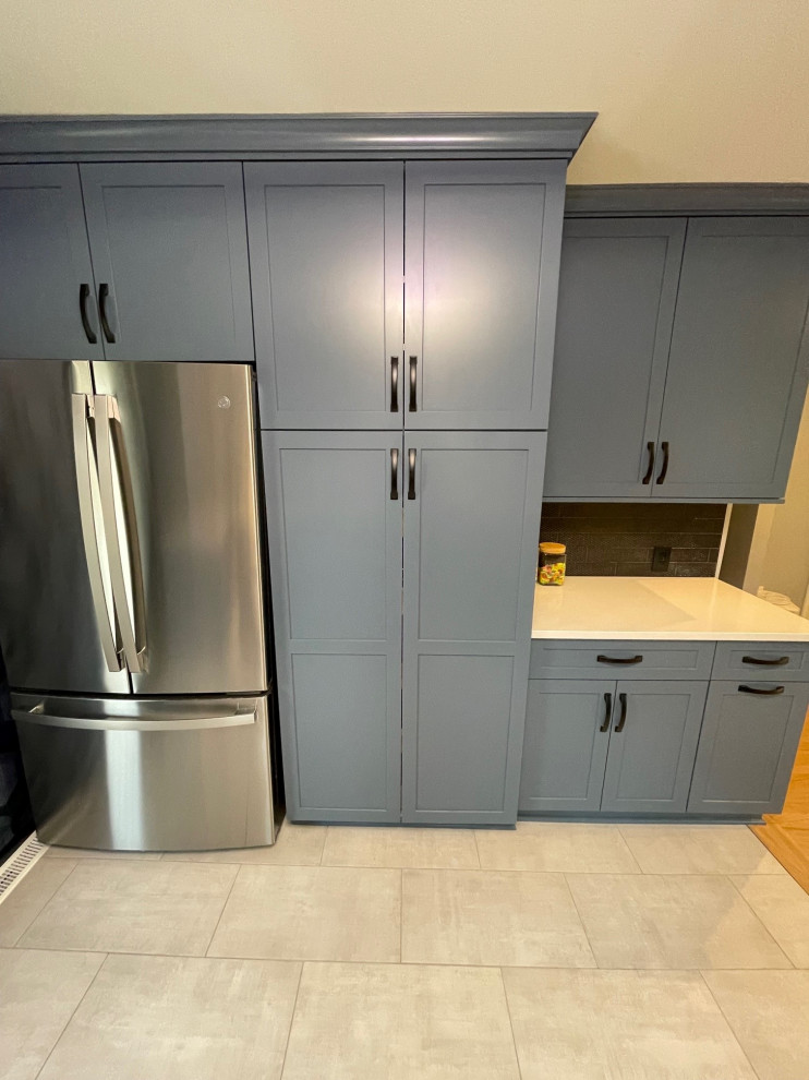 Small eclectic u-shaped kitchen pantry in Detroit with an undermount sink, shaker cabinets, blue cabinets, quartz benchtops, black splashback, stainless steel appliances, porcelain floors, no island, white floor and white benchtop.