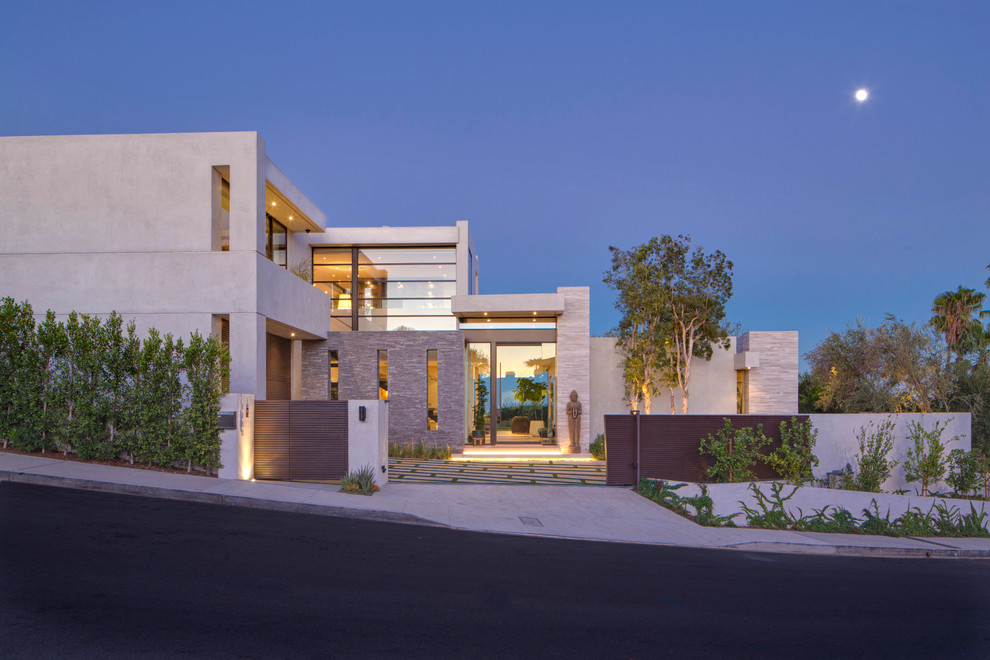 This is an example of an expansive contemporary two-storey beige house exterior in Los Angeles with stone veneer and a flat roof.