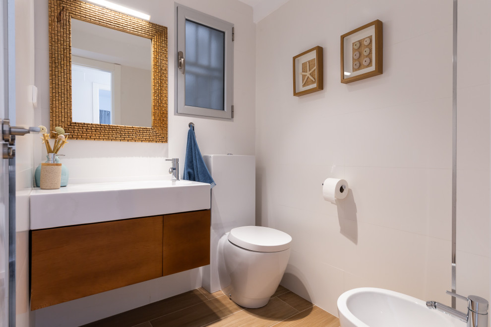This is an example of a mid-sized beach style 3/4 bathroom in Other with flat-panel cabinets, brown cabinets, a one-piece toilet, white walls, an integrated sink, beige floor and white benchtops.