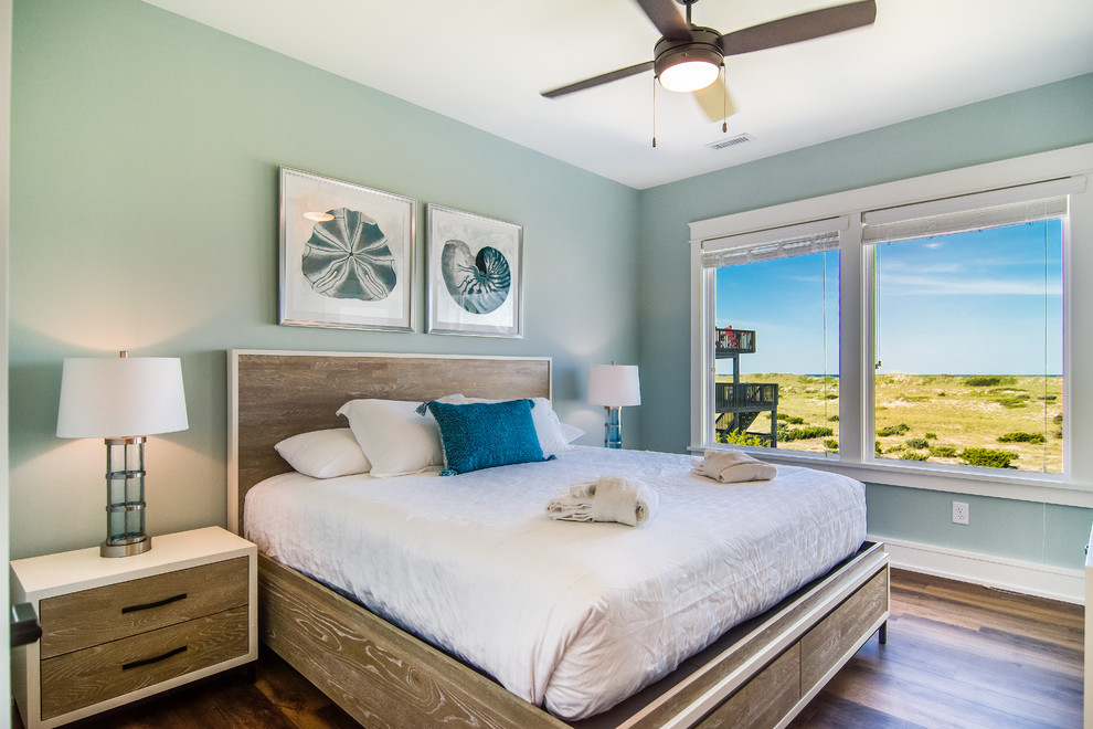 This is an example of a beach style guest bedroom in Other with blue walls, dark hardwood floors and brown floor.
