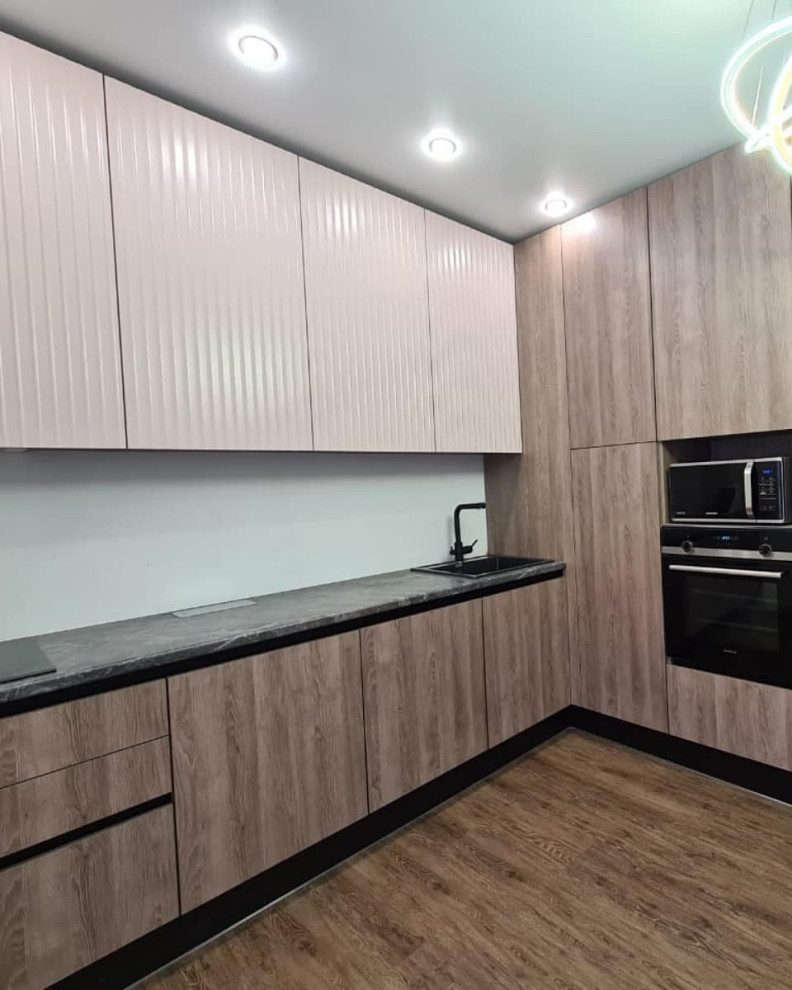 This is an example of a large classic l-shaped kitchen/diner in Moscow with a built-in sink, louvered cabinets, grey cabinets, wood worktops, white splashback, limestone splashback, black appliances, laminate floors, no island, brown floors and black worktops.