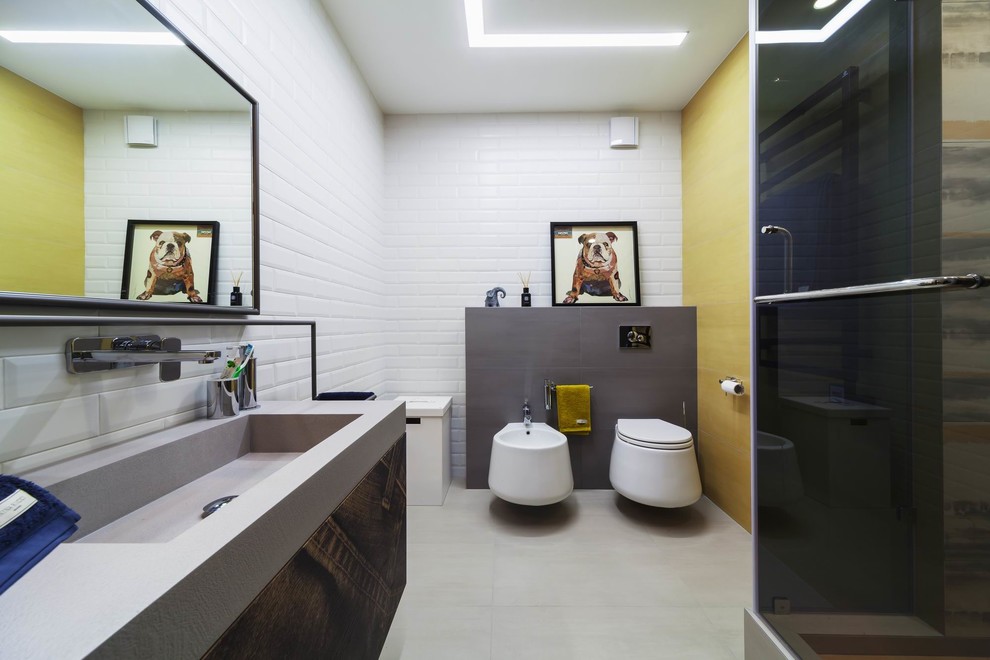 This is an example of a contemporary kids bathroom in Other with flat-panel cabinets, brown cabinets, an alcove shower, white tile, subway tile, a hinged shower door, a bidet, yellow walls, an integrated sink and grey floor.