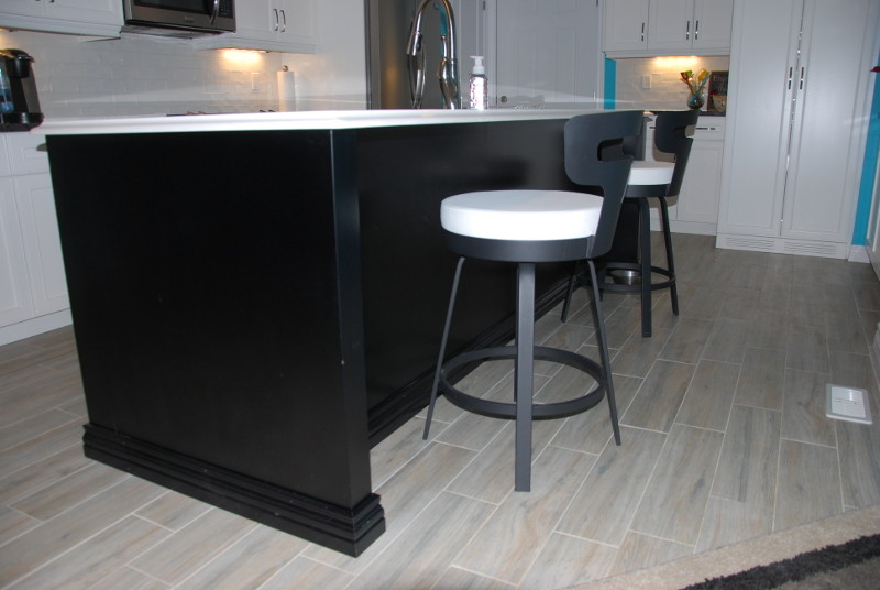 Mid-sized transitional l-shaped porcelain tile and beige floor kitchen photo in Toronto with an undermount sink, recessed-panel cabinets, white cabinets, granite countertops, white backsplash, subway tile backsplash, stainless steel appliances, an island and black countertops
