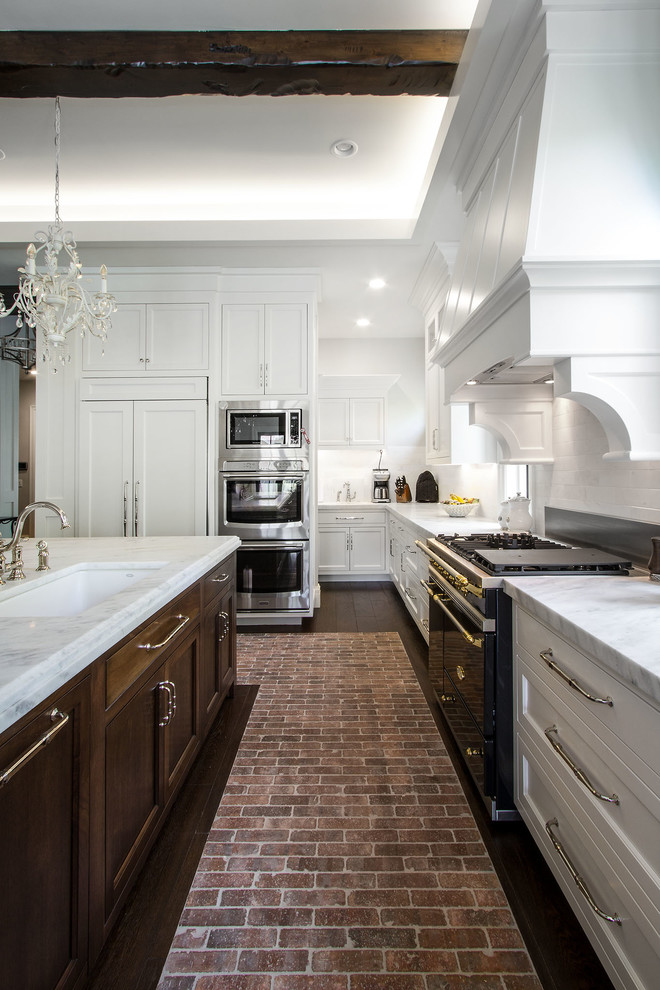 This is an example of a large arts and crafts l-shaped eat-in kitchen in Salt Lake City with an undermount sink, shaker cabinets, white cabinets, marble benchtops, white splashback, subway tile splashback, stainless steel appliances, brick floors and with island.