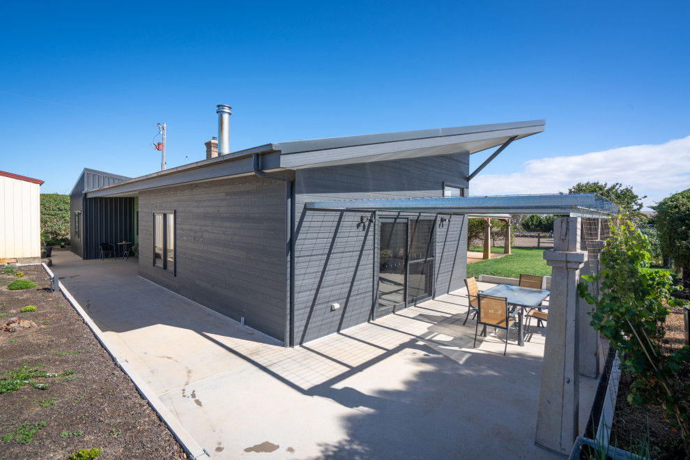 Mittelgroßes, Einstöckiges Modernes Einfamilienhaus mit grauer Fassadenfarbe, Schmetterlingsdach und Blechdach in Sonstige