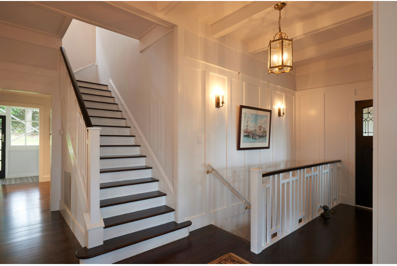 Inspiration for a mid-sized transitional wood u-shaped staircase in Kansas City with painted wood risers, wood railing and decorative wall panelling.