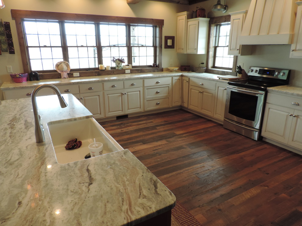 Large mountain style u-shaped dark wood floor eat-in kitchen photo with a farmhouse sink, raised-panel cabinets, white cabinets, marble countertops, stainless steel appliances and an island
