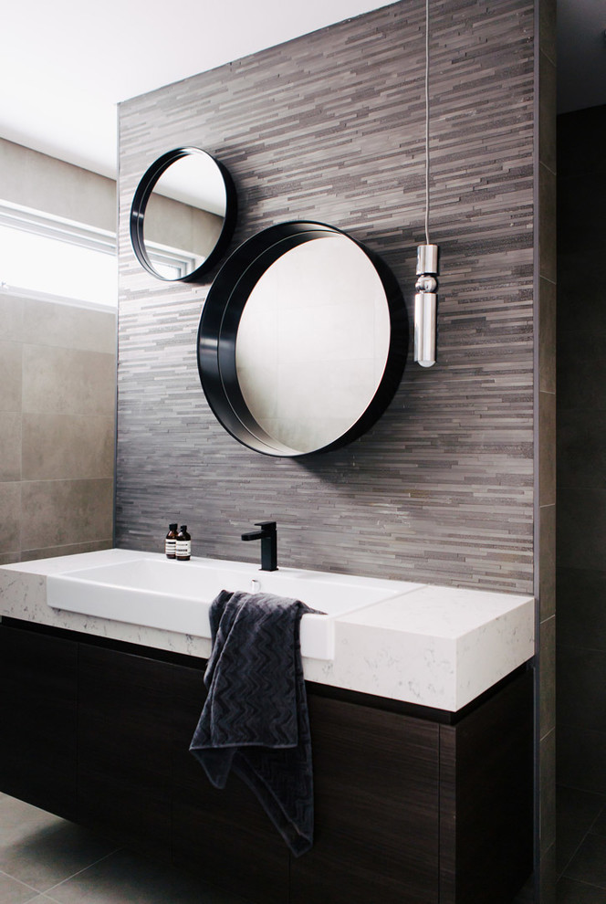 Photo of a contemporary bathroom in Sydney with flat-panel cabinets, black cabinets, a one-piece toilet, black tile, gray tile, cement tile, grey walls, cement tiles and marble benchtops.
