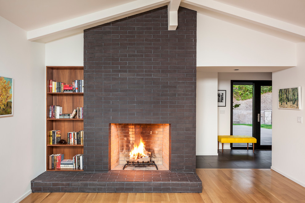 Photo of a mid-sized midcentury formal enclosed living room in San Francisco with a brick fireplace surround, white walls, medium hardwood floors, a standard fireplace, no tv and brown floor.