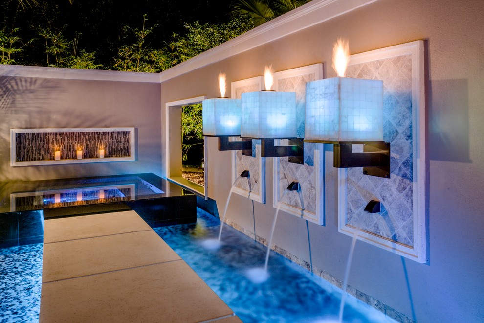 Large modern backyard custom-shaped pool in Tampa with a water feature and natural stone pavers.