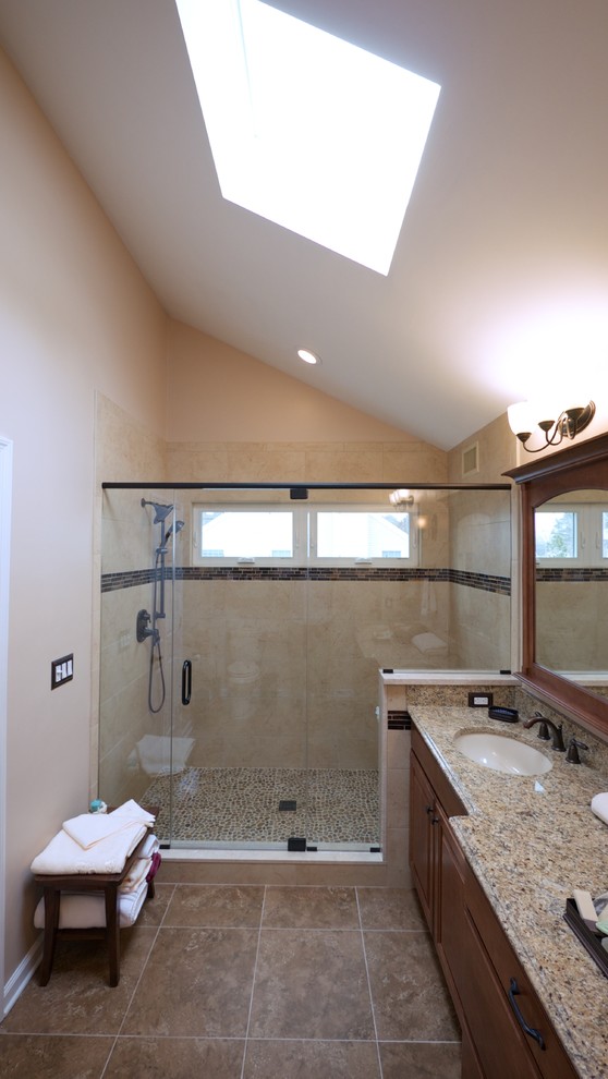 Photo of a mid-sized traditional master bathroom in Philadelphia with an undermount sink, raised-panel cabinets, medium wood cabinets, granite benchtops, an open shower, brown tile, glass tile, beige walls and porcelain floors.