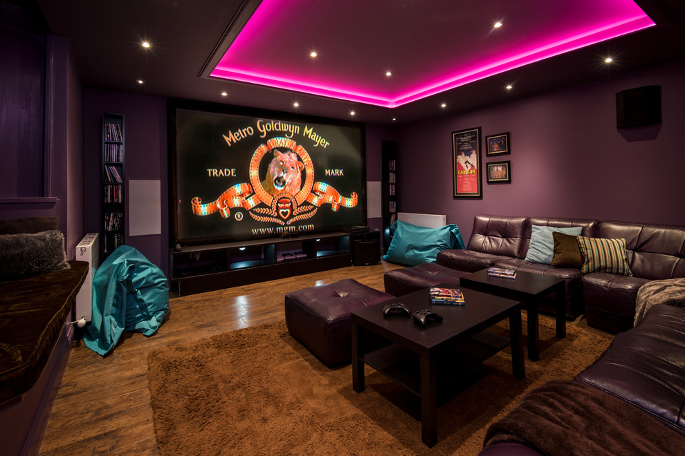 Mid-sized traditional enclosed home theatre in Other with purple walls, medium hardwood floors, a projector screen and brown floor.
