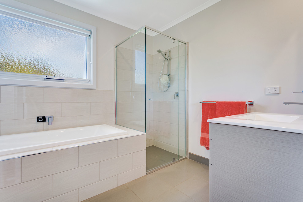 Photo of a mid-sized contemporary master bathroom in Melbourne with raised-panel cabinets, grey cabinets, a drop-in tub, a corner shower, beige tile, ceramic tile, beige walls, ceramic floors, an integrated sink and engineered quartz benchtops.