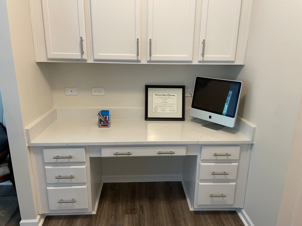 Example of a small minimalist built-in desk laminate floor, brown floor, coffered ceiling and wall paneling study room design in Raleigh with white walls and no fireplace
