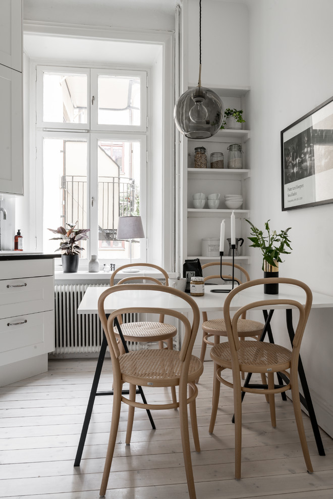 Photo of a scandinavian kitchen/dining combo in Stockholm with white walls, light hardwood floors and beige floor.