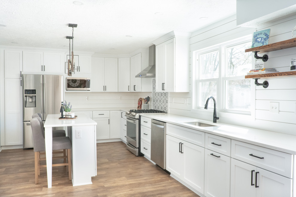 Kitchen pantry - mid-sized coastal l-shaped medium tone wood floor and brown floor kitchen pantry idea in Baltimore with an undermount sink, shaker cabinets, white cabinets, quartz countertops, white backsplash, shiplap backsplash, stainless steel appliances, an island and white countertops