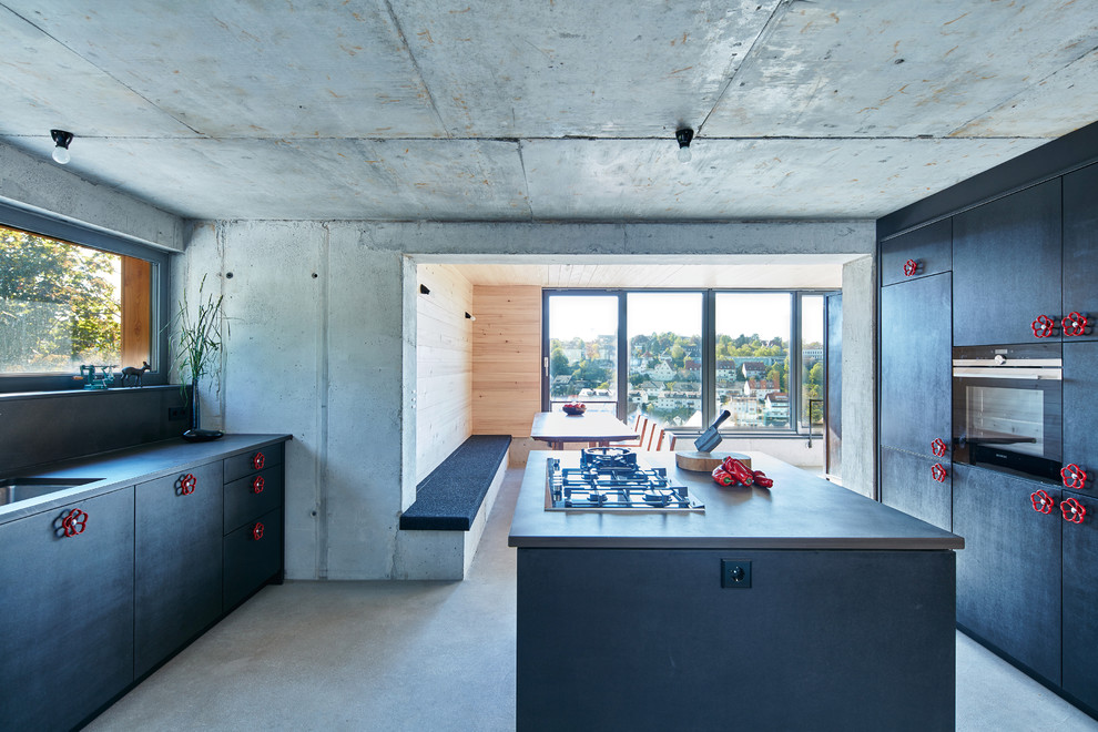 Design ideas for an industrial galley separate kitchen in Stuttgart with an undermount sink, flat-panel cabinets, black cabinets, concrete benchtops, grey splashback, black appliances, concrete floors, with island and grey floor.