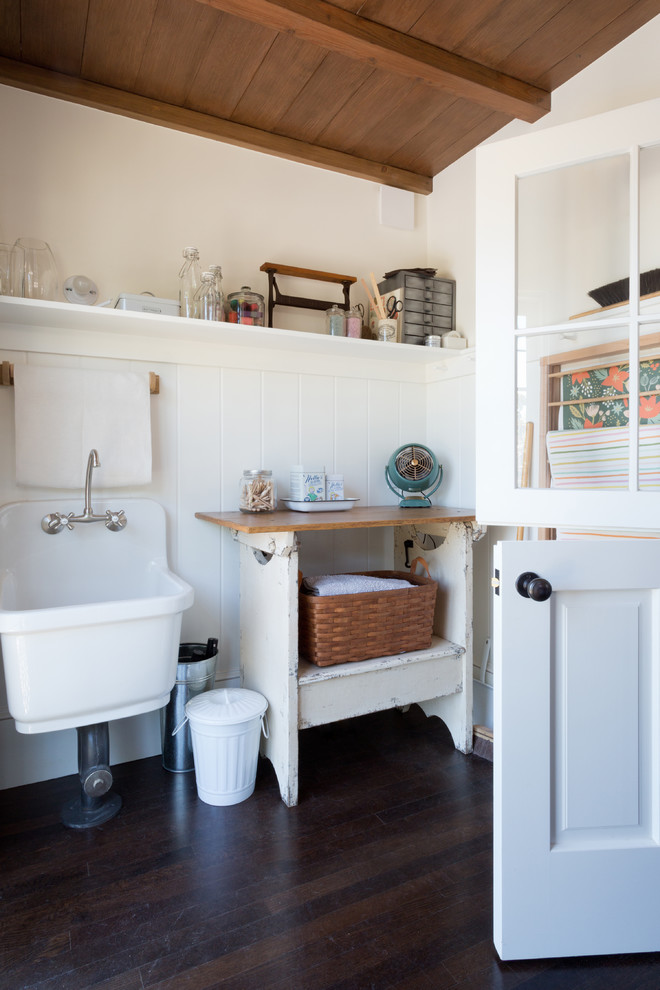 Ejemplo de cuarto de lavado de estilo de casa de campo pequeño con fregadero de un seno, encimera de madera, paredes blancas, suelo de madera oscura y encimeras beige