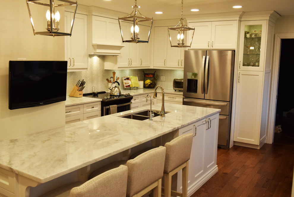 Example of a transitional kitchen design with an undermount sink, stainless steel appliances, an island and white countertops