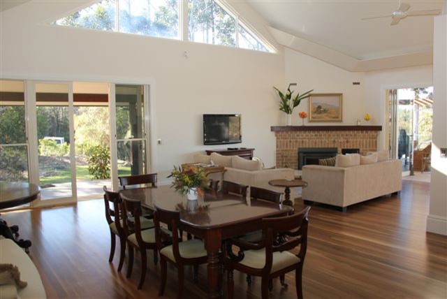 This is an example of a large traditional open plan dining in Sunshine Coast with white walls, light hardwood floors, a brick fireplace surround and brown floor.