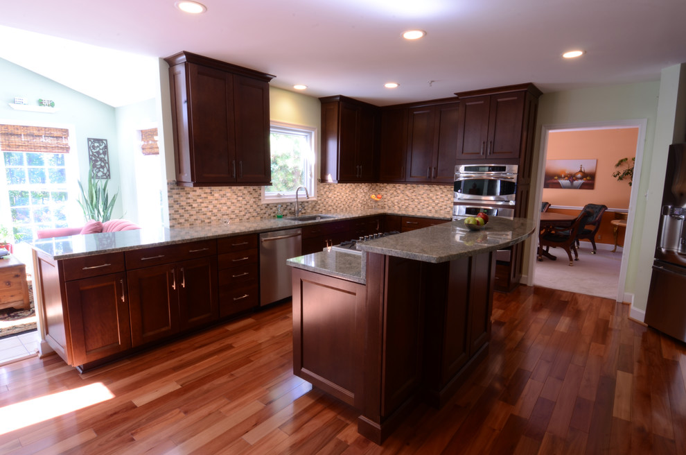 Large transitional u-shaped medium tone wood floor and brown floor eat-in kitchen photo in Baltimore with an undermount sink, flat-panel cabinets, dark wood cabinets, granite countertops, green backsplash, stainless steel appliances, green walls, matchstick tile backsplash and an island