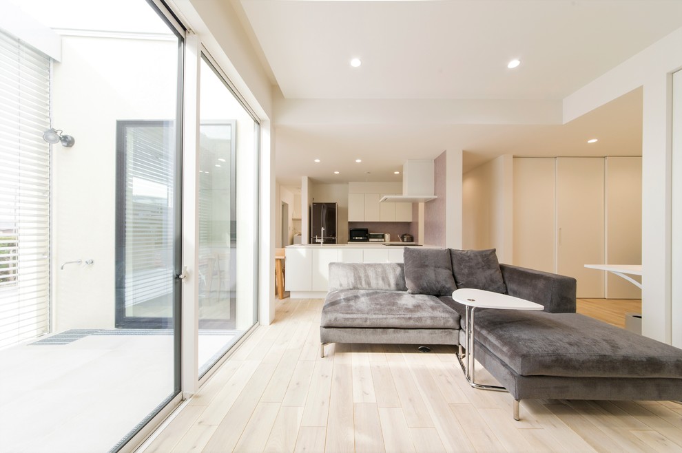 Photo of a modern open concept living room in Other with white walls, light hardwood floors and white floor.