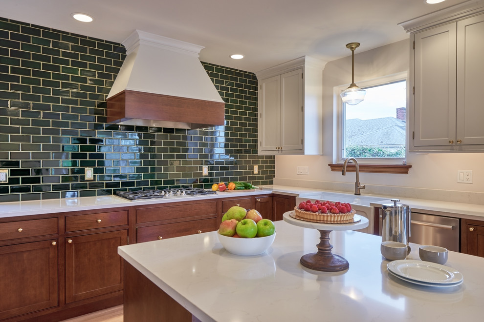Example of a mid-sized transitional u-shaped medium tone wood floor kitchen design in Seattle with a farmhouse sink, beaded inset cabinets, white cabinets, quartz countertops, green backsplash, porcelain backsplash, stainless steel appliances, an island and white countertops