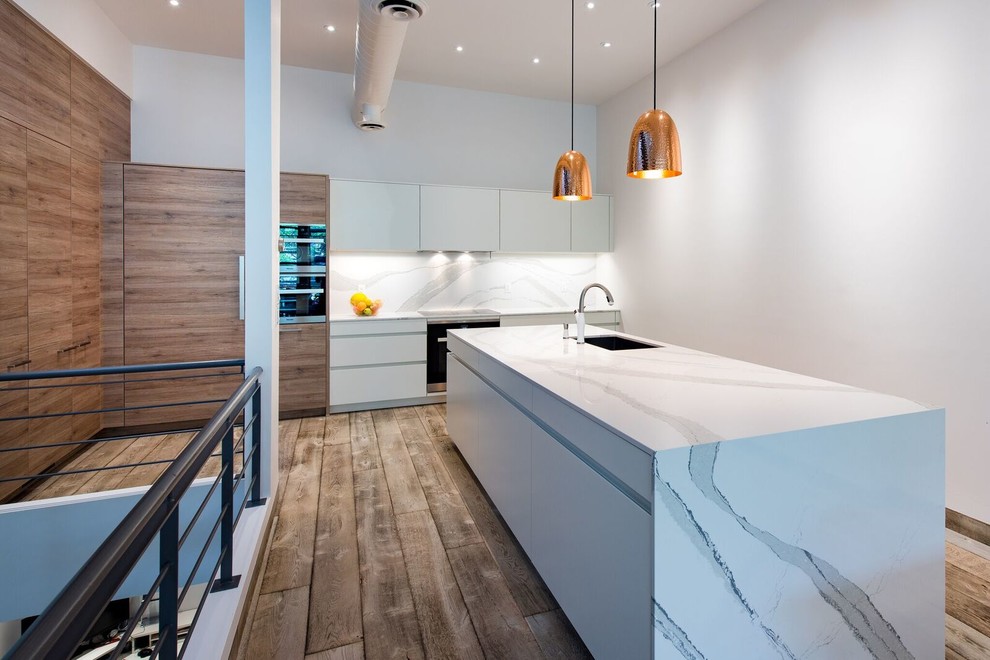 Example of a mid-sized transitional galley medium tone wood floor eat-in kitchen design in Toronto with an undermount sink, flat-panel cabinets, medium tone wood cabinets, quartz countertops, white backsplash, stainless steel appliances and an island