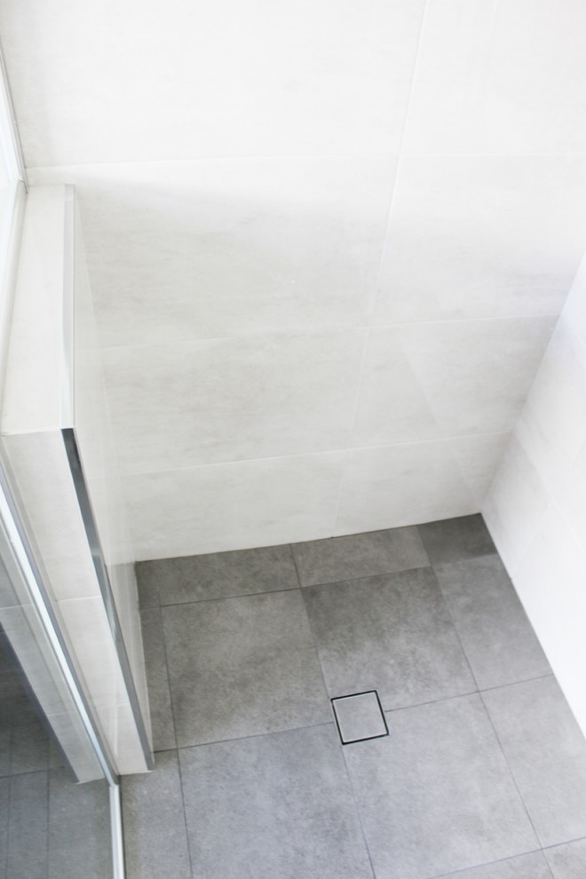 Inspiration for a small kids bathroom in Perth with flat-panel cabinets, dark wood cabinets, a freestanding tub, a corner shower, gray tile, porcelain tile, grey walls, porcelain floors, an integrated sink, solid surface benchtops, grey floor, a hinged shower door and white benchtops.