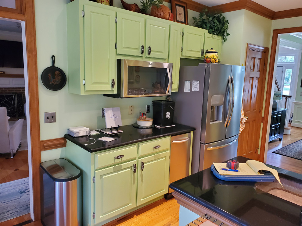 Exempel på ett mellanstort klassiskt svart svart kök, med en dubbel diskho, skåp i shakerstil, gröna skåp, granitbänkskiva, rostfria vitvaror, ljust trägolv, en halv köksö och gult golv