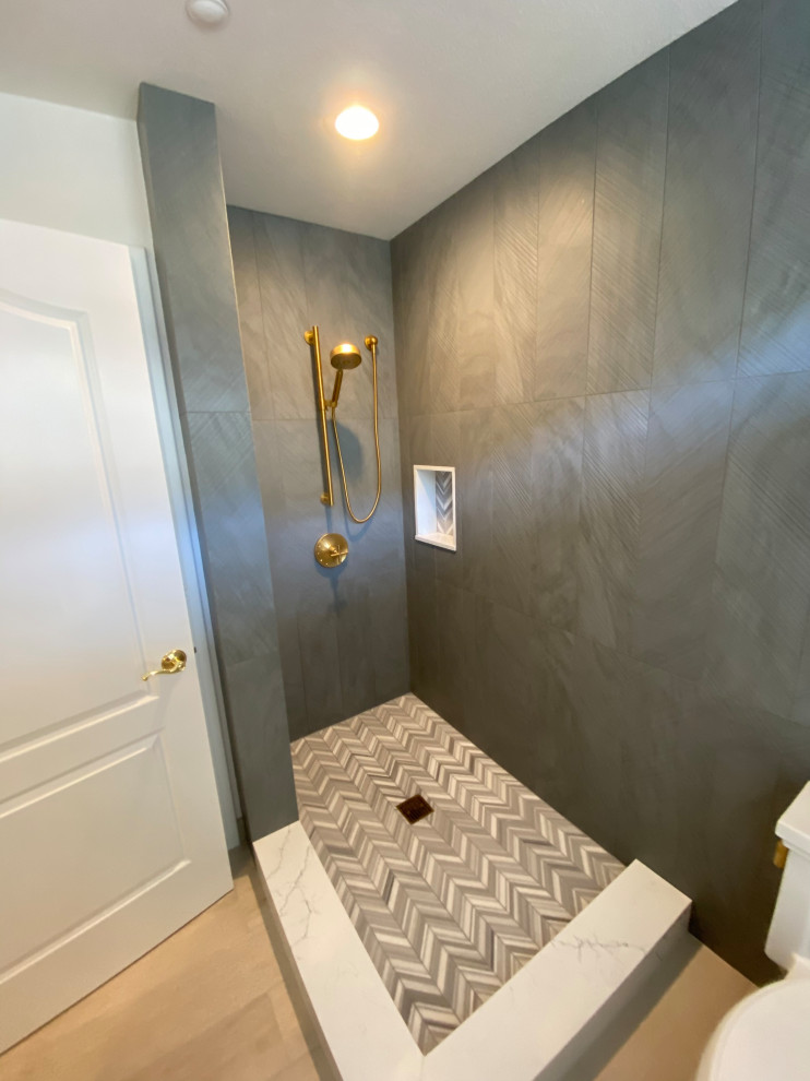 Photo of a mid-sized transitional master bathroom in Other with a corner shower, a two-piece toilet, gray tile, grey walls, light hardwood floors, a hinged shower door, a single vanity and a built-in vanity.