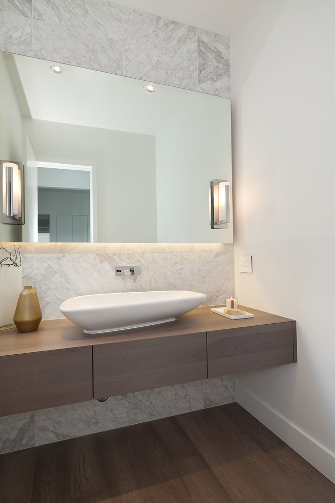 Photo of a mid-sized contemporary powder room in Vancouver with a vessel sink, flat-panel cabinets, wood benchtops, white walls, dark hardwood floors, white tile, dark wood cabinets, marble and brown benchtops.
