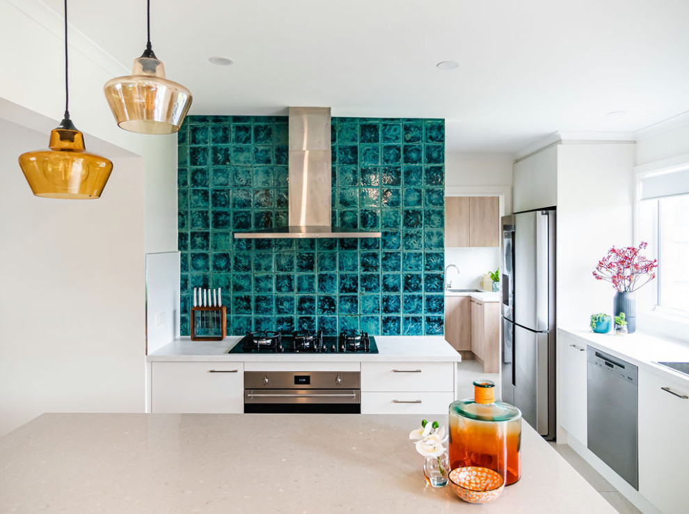 Photo of a mid-sized modern l-shaped open plan kitchen in Melbourne with a double-bowl sink, flat-panel cabinets, white cabinets, quartz benchtops, blue splashback, ceramic splashback, stainless steel appliances, porcelain floors, with island, beige floor and white benchtop.