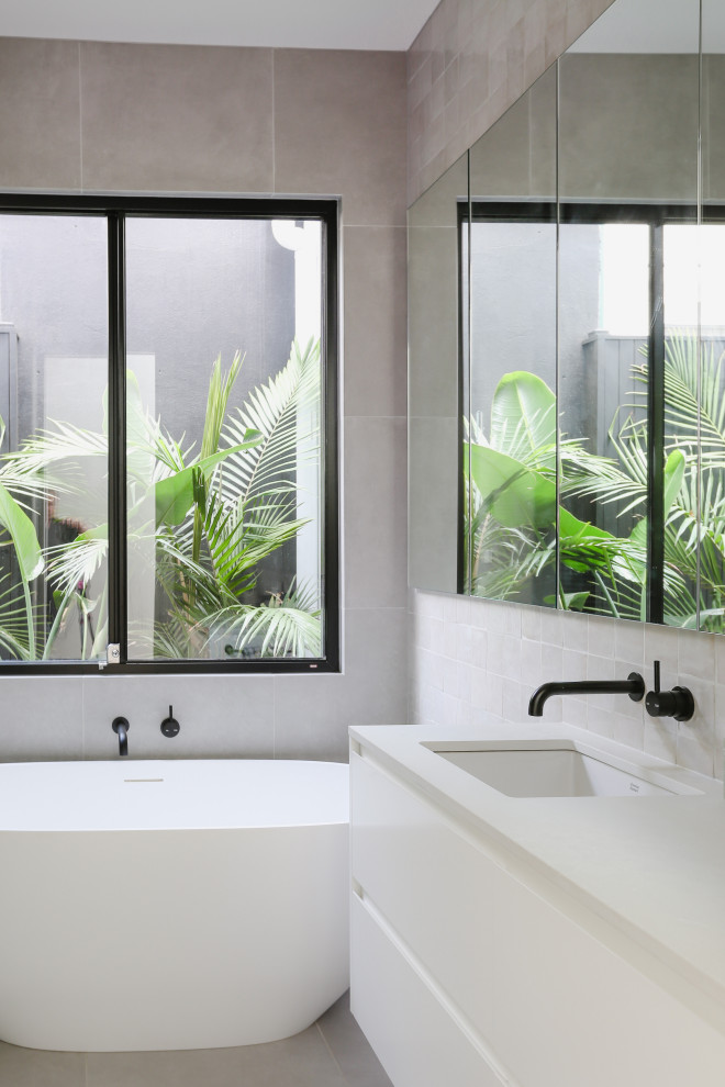 Inspiration for a contemporary bathroom in Melbourne with flat-panel cabinets, white cabinets, a freestanding tub, gray tile, an undermount sink, grey floor, white benchtops and a floating vanity.