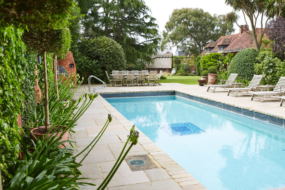 Photo of a mid-sized traditional backyard rectangular lap pool in Sussex with natural stone pavers.