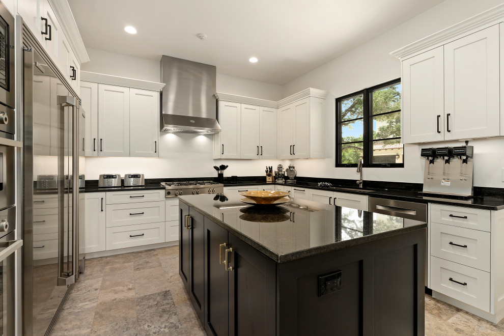 Enclosed kitchen - huge u-shaped enclosed kitchen idea with white cabinets, stainless steel appliances, an island and black countertops