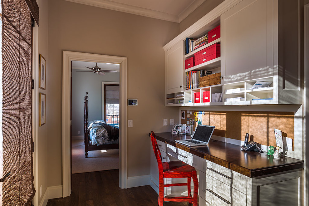 This is an example of a mid-sized transitional study room in Other with beige walls, dark hardwood floors, no fireplace and a built-in desk.