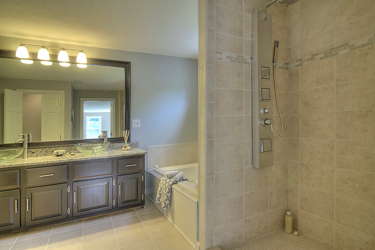 This is an example of a mid-sized traditional master bathroom in Boston with a vessel sink, raised-panel cabinets, black cabinets, granite benchtops, a hot tub, an alcove shower, a two-piece toilet, beige tile, ceramic tile, grey walls and ceramic floors.