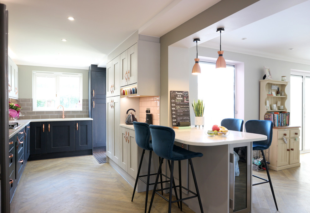 Mid-sized minimalist u-shaped vinyl floor and brown floor eat-in kitchen photo in Hertfordshire with a farmhouse sink, shaker cabinets, gray cabinets, quartzite countertops, gray backsplash, subway tile backsplash, paneled appliances, a peninsula and white countertops