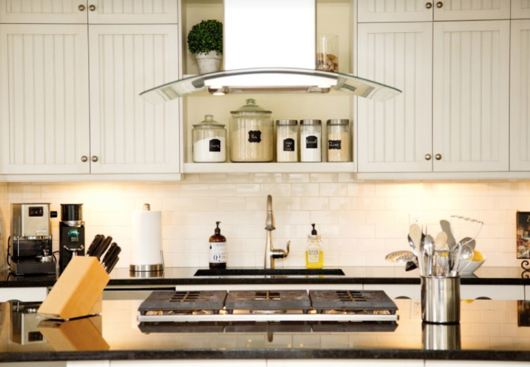 Example of a mid-sized transitional single-wall laminate floor and brown floor open concept kitchen design in Calgary with an undermount sink, louvered cabinets, white cabinets, solid surface countertops, white backsplash, subway tile backsplash, stainless steel appliances and an island